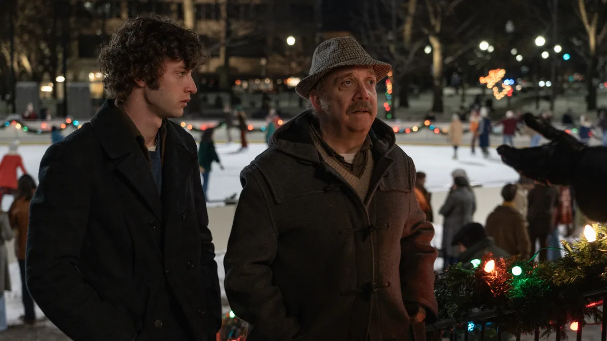 Dominic Sessa as Angus Tully and Paul Giamatti as Paul Hunham at a Christmas skating rink in The Holdovers